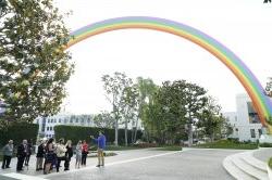 一群人站在一个巨大的彩虹雕塑前
