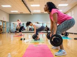 Two people in a group fitness class lifting weights
