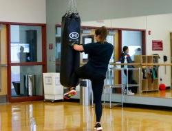 A female punching and kneeing a punching bag.