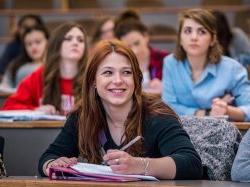photo of female student smiling and taking notes in class