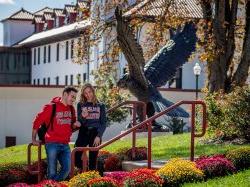 Two students talking next to the red hawk statue