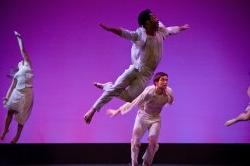 Photo of dancers in white leaping through the air.