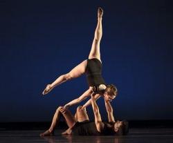 Photo of two dancers, one lifted upside-down with leg in the air.