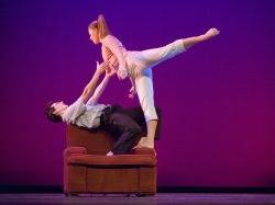Photo of dancers in dramatic pose on a recliner chair.