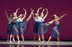 Photo of six dancers in flowing lavender skirts.