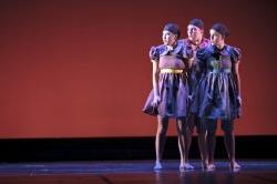 Photo of trio of dancers standing close on stage.