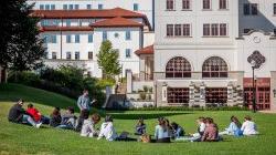 十大博彩推荐排名州立大学费利西亚诺商学院，一名老师站在草地上，学生们坐在草地上
