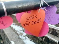 Some paper hearts on a railing with inspirational messages.